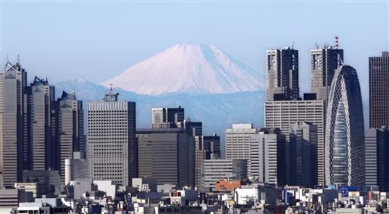 Japan's highest peak, Mount Fuji, looms over high-rise buildings of Tokyo's Shinjuku district. Japan confirmed Monday that China's economy surpassed its own as the world's second largest in 2010 and said a late-year downturn was Japan's first quarterly contraction in more than a year.